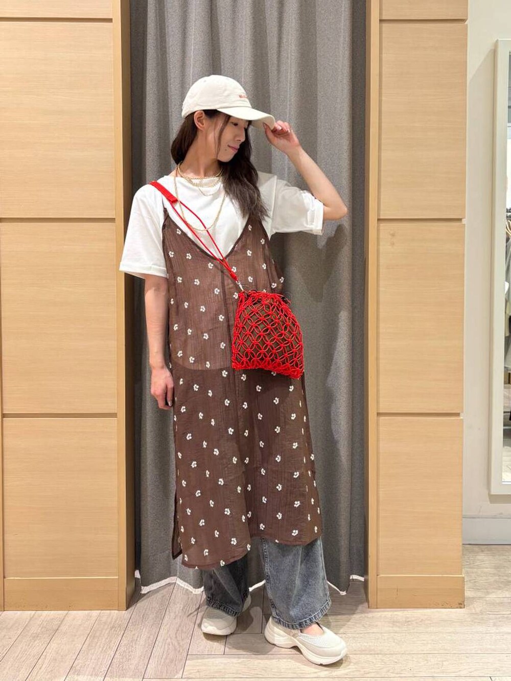 グレー系のデニムパンツ、レッド系のショルダーバッグ、ベージュ系のスニーカーを着用したレディースの春コーディネートの3枚目の写真