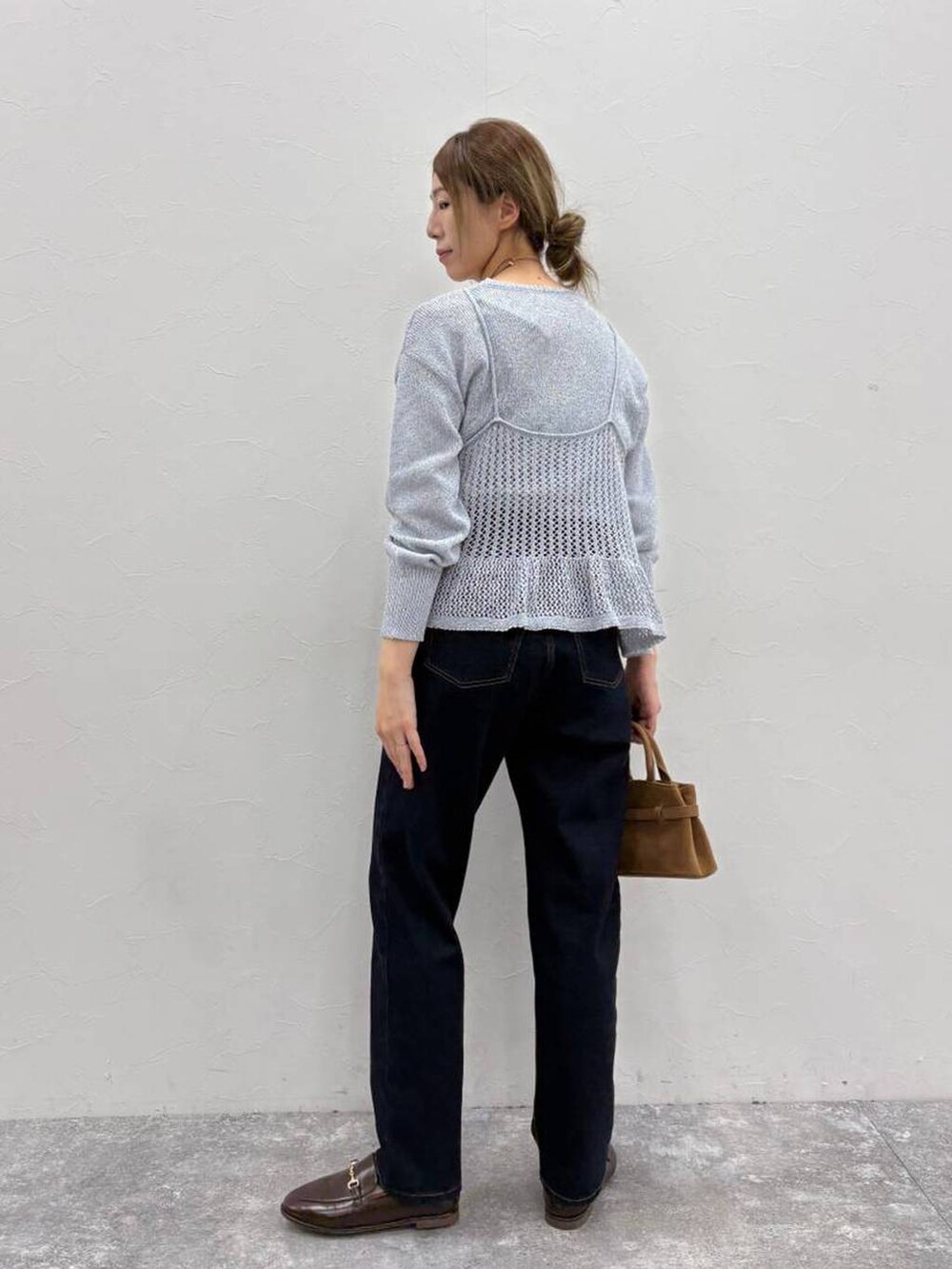 ブラウン系のショルダーバッグ、ブルー系のデニムパンツ、ブルー系のニット/セーターを着用したレディースの春コーディネートの3枚目の写真