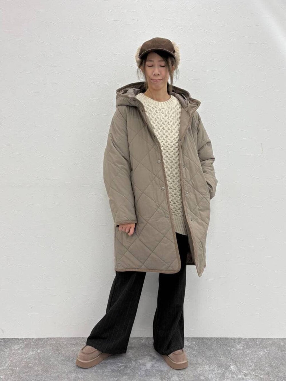 グレー系のブーツ、ブラウン系のダウンジャケット/コート、グレー系のスラックスを着用したレディースの冬コーディネートの2枚目の写真