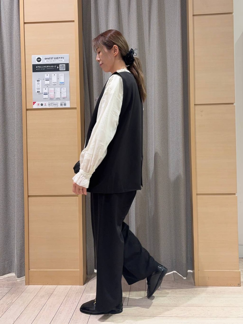 ブラック系のベスト、ブラック系のスラックス、ブラック系のショルダーバッグを着用したレディースの春コーディネートの3枚目の写真