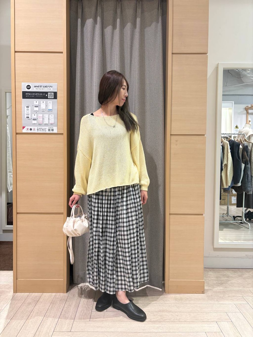 ベージュ系のショルダーバッグ、イエロー系のニット/セーター、ブラック系のスカートを着用したレディースの冬コーディネートの3枚目の写真