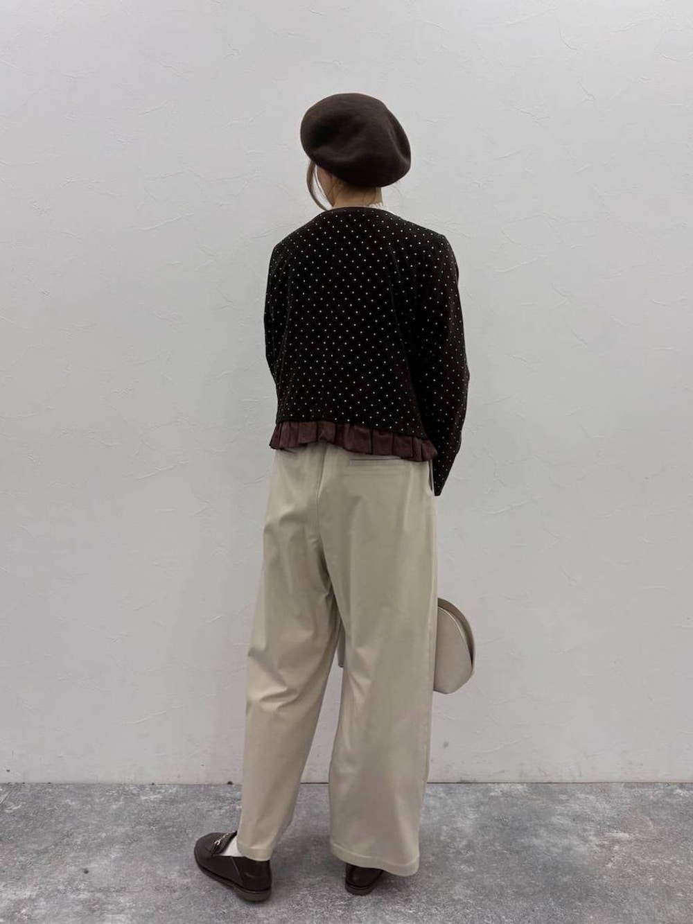 ベージュ系のスラックス、ベージュ系のトートバッグ、ホワイト系のシャツ/ブラウスを着用したレディースの冬コーディネートの3枚目の写真