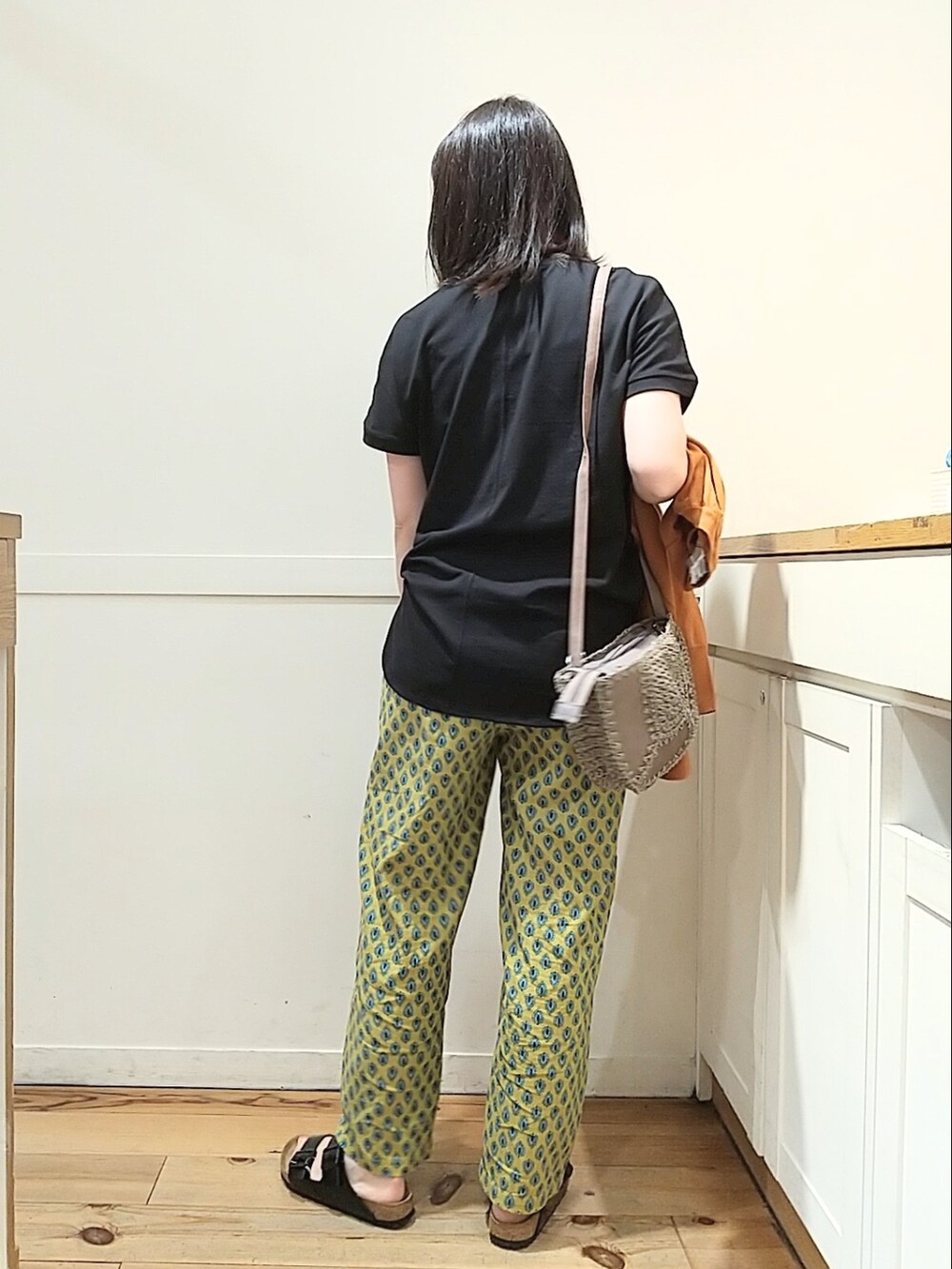 イエロー系のその他パンツ、ブラック系のTシャツ/カットソー、ブラック系のサンダルを着用したレディースの春コーディネートの2枚目の写真