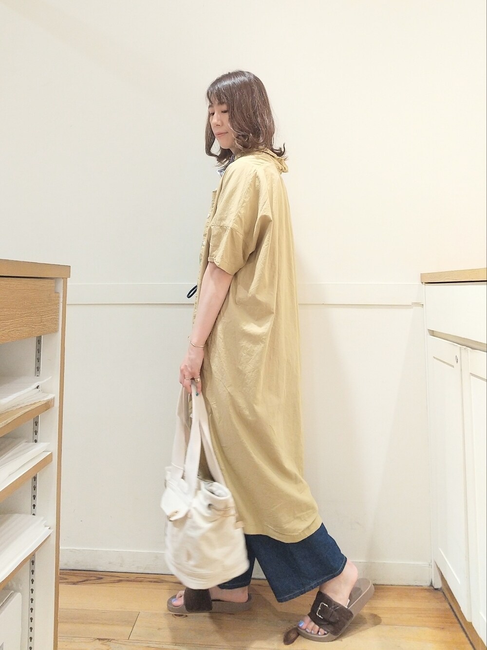 ブラウン系のサンダル、ベージュ系のトートバッグ、グリーン系のTシャツ/カットソーを着用したレディースの夏コーディネートの3枚目の写真