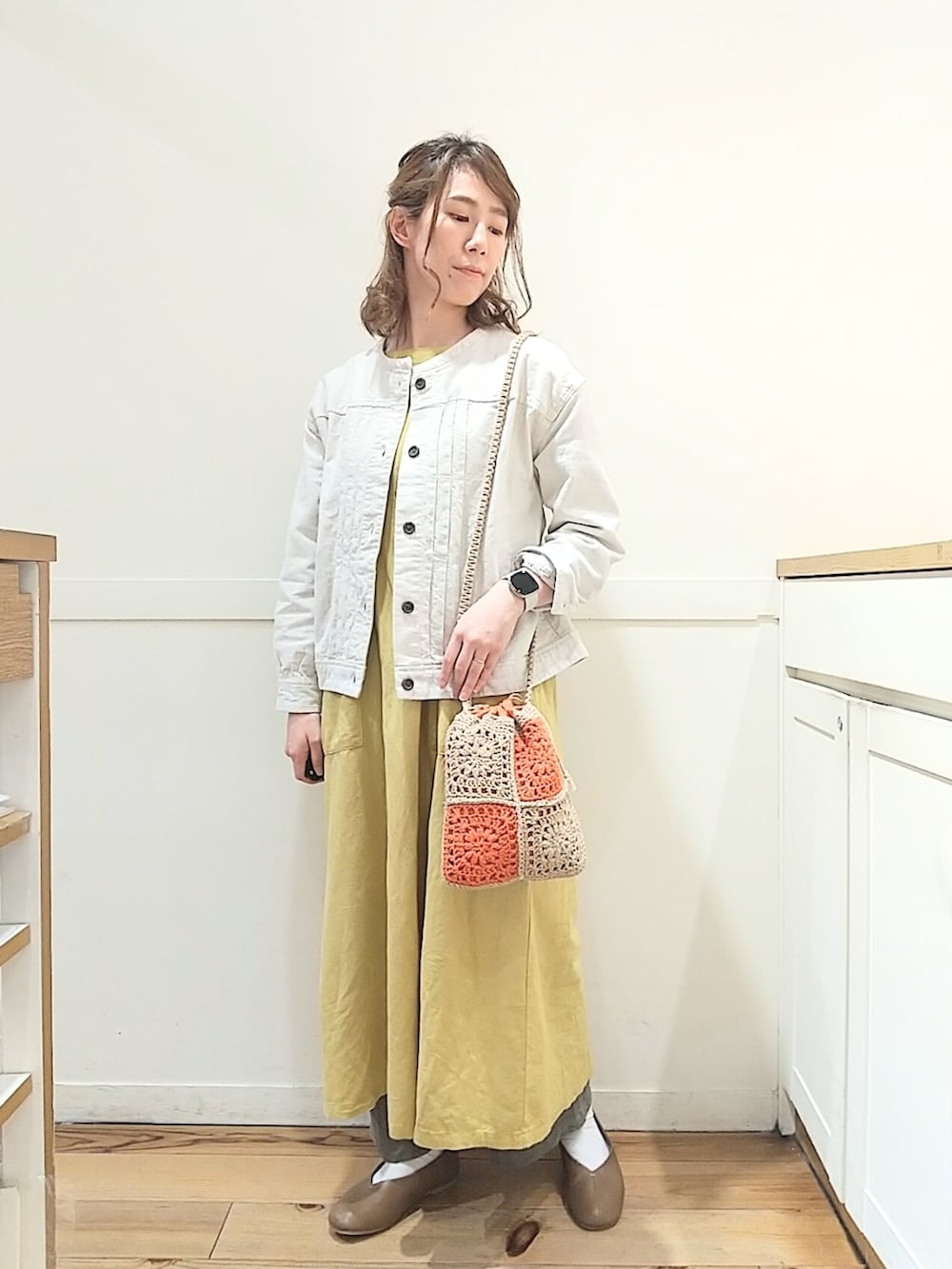 ベージュ系のショルダーバッグ、イエロー系のワンピース、ベージュ系のブルゾンを着用したレディースの春コーディネートの2枚目の写真