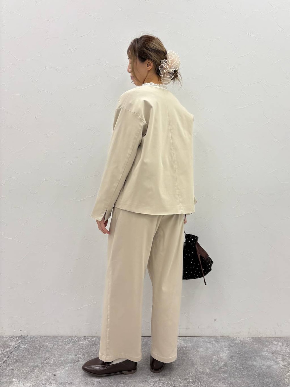 ベージュ系のスラックス、ベージュ系のノーカラージャケット、ホワイト系のシャツ/ブラウスを着用したレディースの冬コーディネートの3枚目の写真