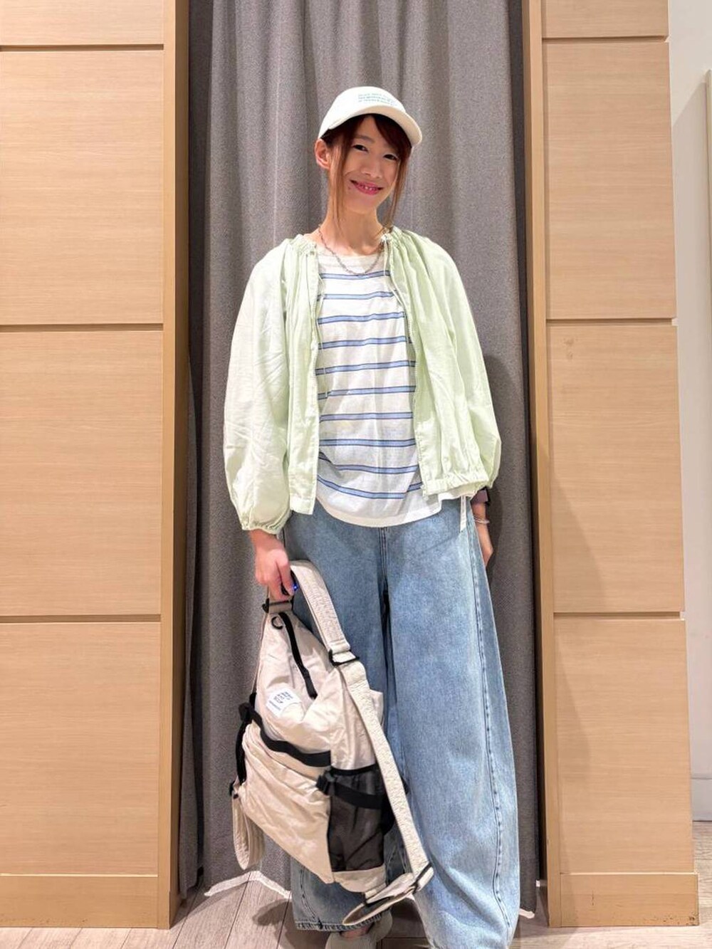 ブルー系のデニムパンツ、ベージュ系のショルダーバッグ、その他のニット/セーターを着用したレディースの春コーディネートの4枚目の写真
