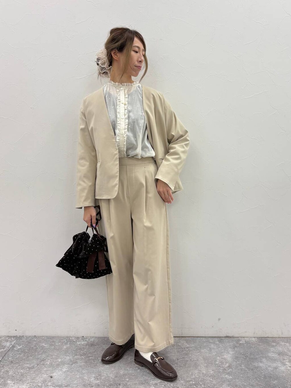 ベージュ系のスラックス、ベージュ系のノーカラージャケット、ホワイト系のシャツ/ブラウスを着用したレディースの冬コーディネートの2枚目の写真