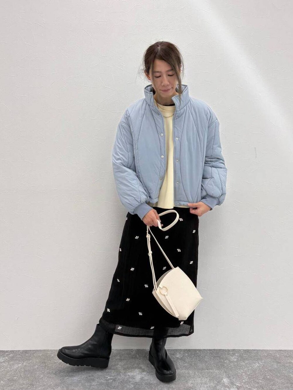 ブラック系のブーツ、ベージュ系のショルダーバッグ、ホワイト系のニット/セーターを着用したレディースの冬コーディネートの2枚目の写真