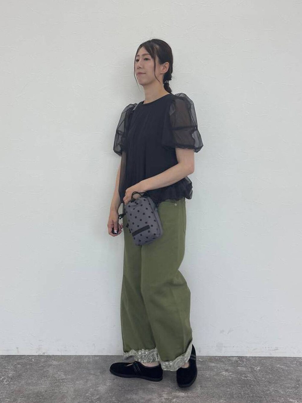 グリーン系のデニムパンツ、グレー系のショルダーバッグ、ブラック系のスニーカーを着用したレディースの秋コーディネートの3枚目の写真
