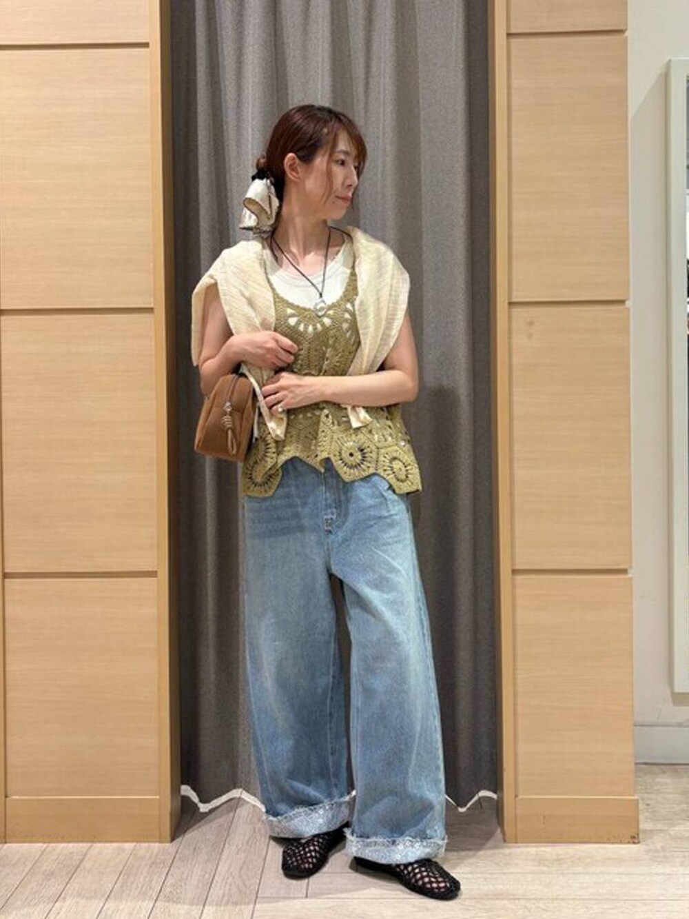 ブラウン系のショルダーバッグ、ブルー系のデニムパンツ、ベージュ系のタンクトップを着用したレディースの夏コーディネートの4枚目の写真
