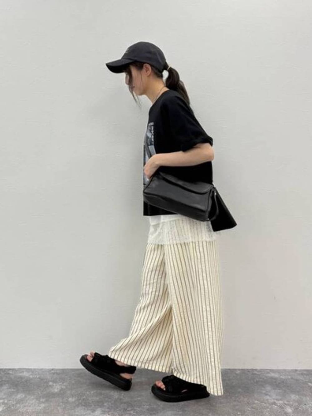 ブラック系のサンダル、ブラック系のTシャツ/カットソー、ブラック系のショルダーバッグを着用したレディースの夏コーディネートの3枚目の写真