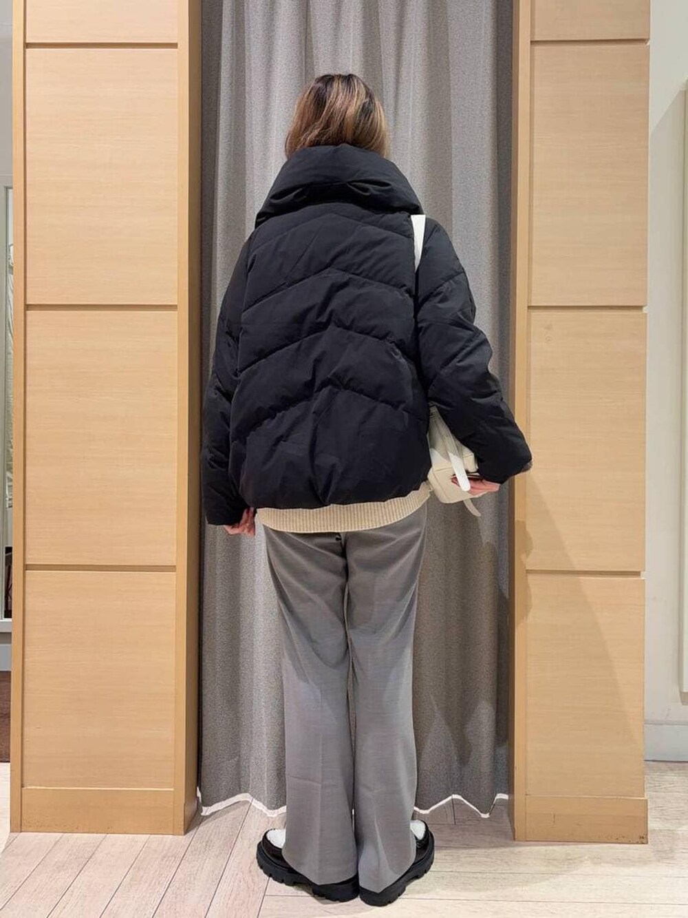 ブラック系のダウンジャケット/コート、ベージュ系のニット/セーター、ベージュ系のショルダーバッグを着用したレディースの秋コーディネートの3枚目の写真