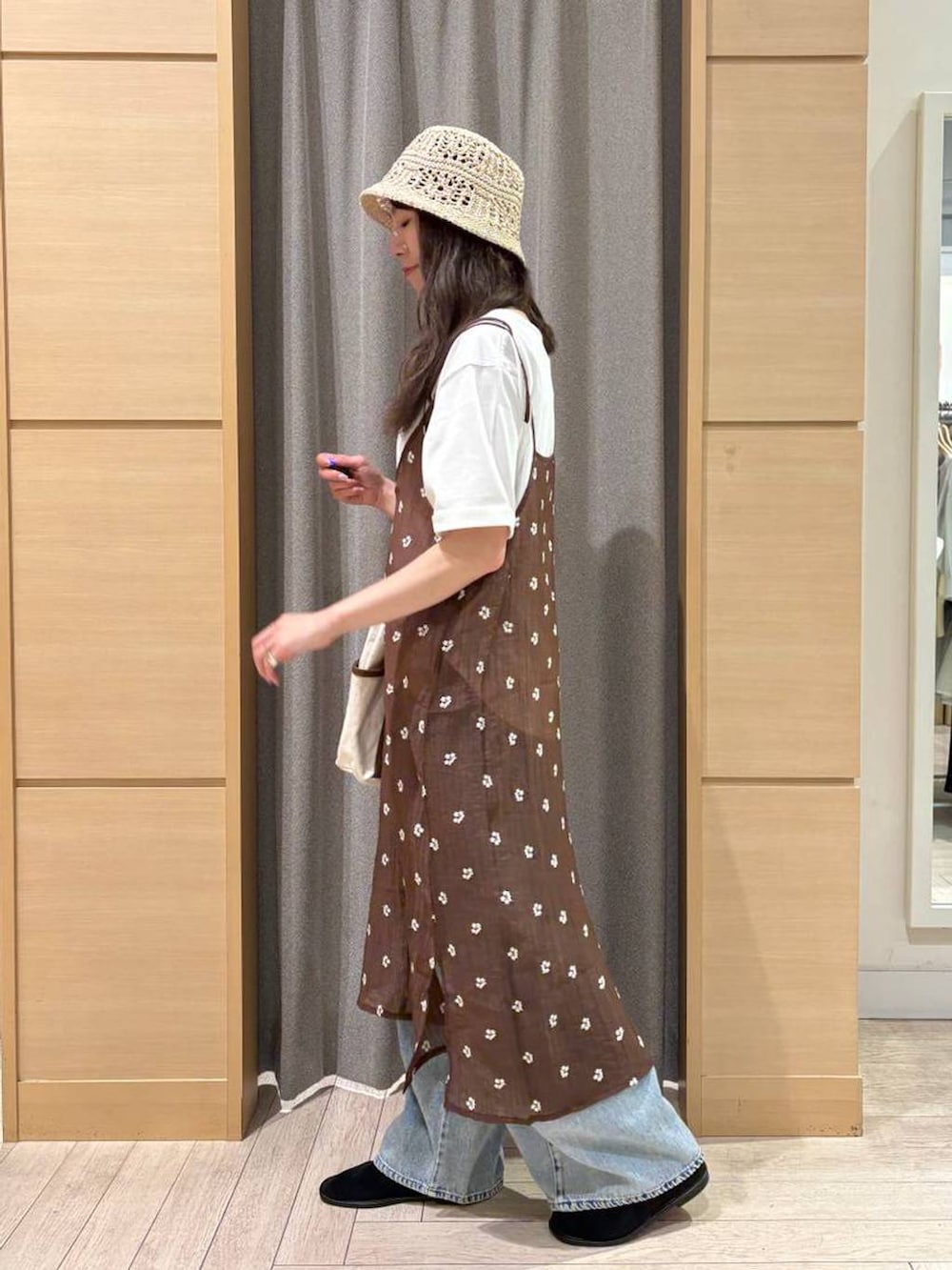 ブルー系のデニムパンツ、ベージュ系のトートバッグ、ブラック系のパンプスを着用したレディースの夏コーディネートの2枚目の写真