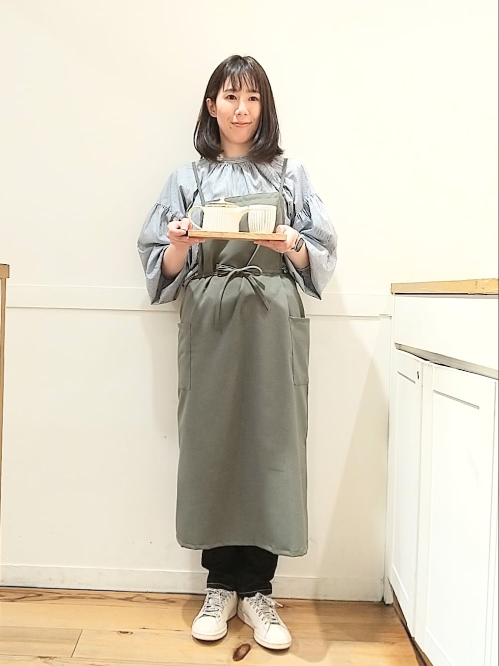 ブルー系のシャツ/ブラウス、ブラック系のデニムパンツ、グリーン系のエプロンを着用したレディースの春コーディネートの2枚目の写真