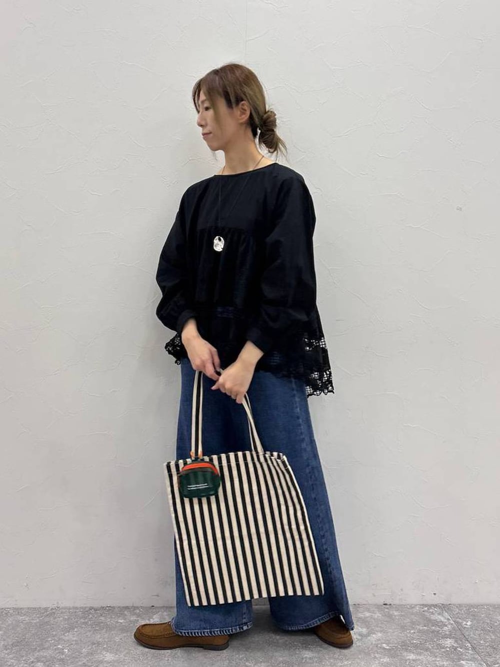 ブルー系のデニムパンツ、イエロー系のローファー、イエロー系のトートバッグを着用したレディースの春コーディネートの2枚目の写真