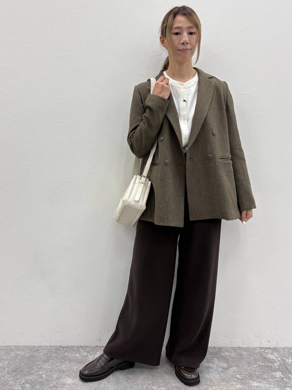 ブラウン系のテーラードジャケット、ホワイト系のシャツ/ブラウス、ブラウン系のローファーを着用したレディースの秋コーディネートの6枚目の写真