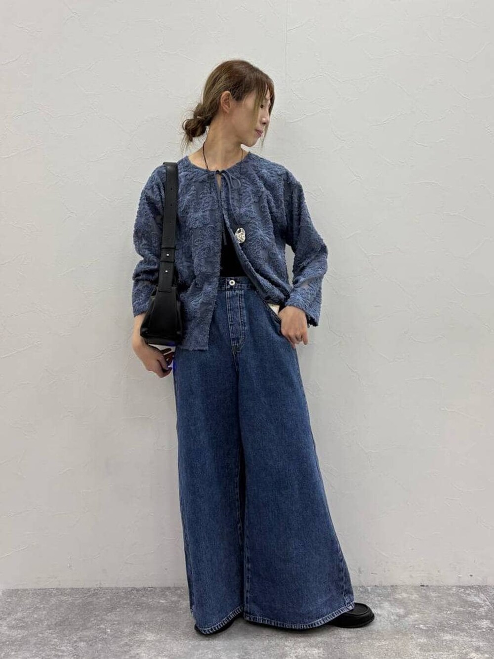 ブラック系のTシャツ/カットソー、ブルー系のデニムパンツ、ブラック系のローファーを着用したレディースの春コーディネートの2枚目の写真