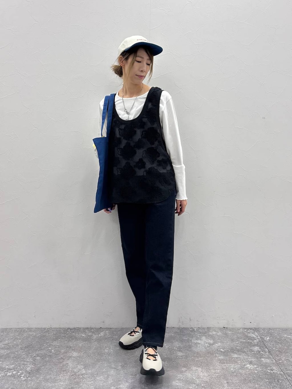 ホワイト系のスニーカー、ブラック系のTシャツ/カットソー、ブルー系のトートバッグを着用したレディースの春コーディネートの2枚目の写真