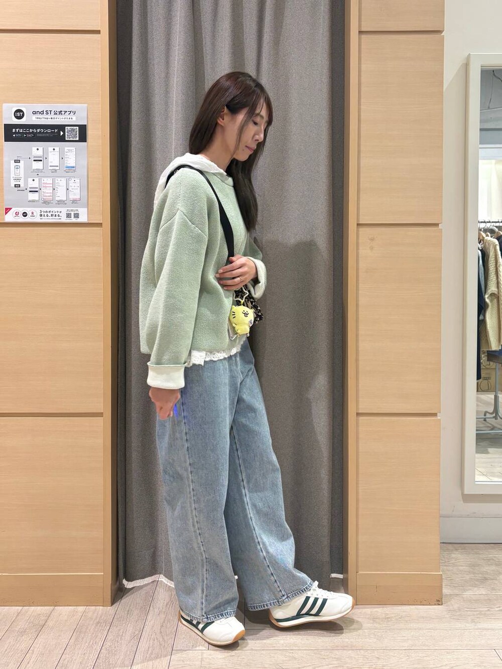 ホワイト系のスニーカー、ブルー系のデニムパンツ、ブラウン系のショルダーバッグを着用したレディースの冬コーディネートの2枚目の写真