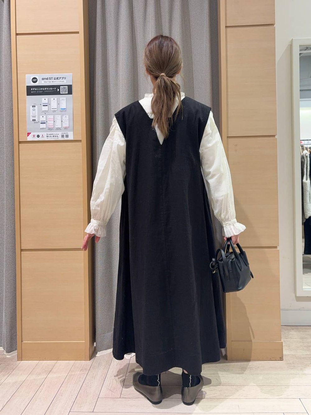 ブラック系のトートバッグ、ホワイト系のシャツ/ブラウス、ブラック系のジャンパースカートを着用したレディースの冬コーディネートの3枚目の写真