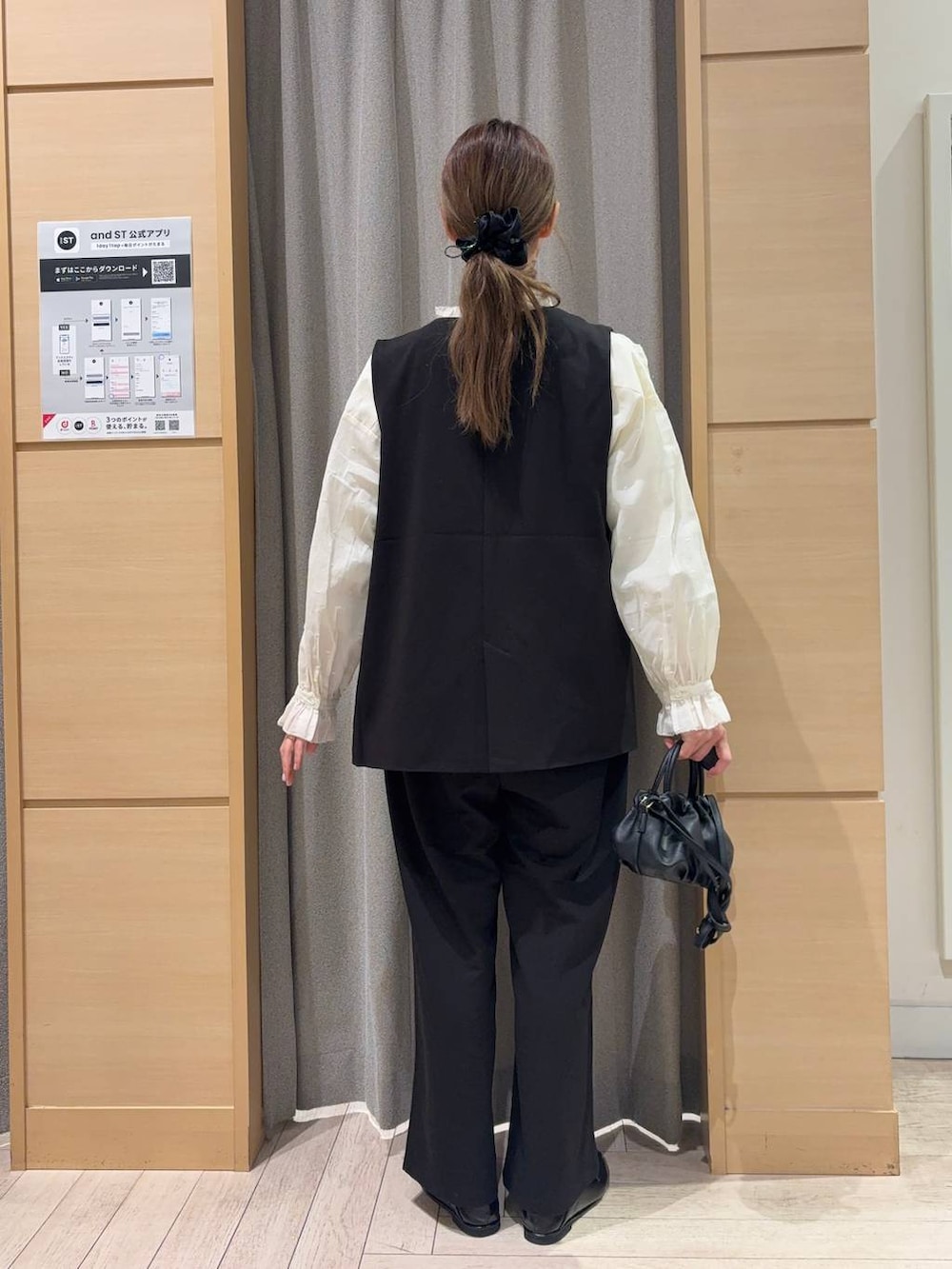 ブラック系のベスト、ブラック系のスラックス、ブラック系のショルダーバッグを着用したレディースの春コーディネートの2枚目の写真