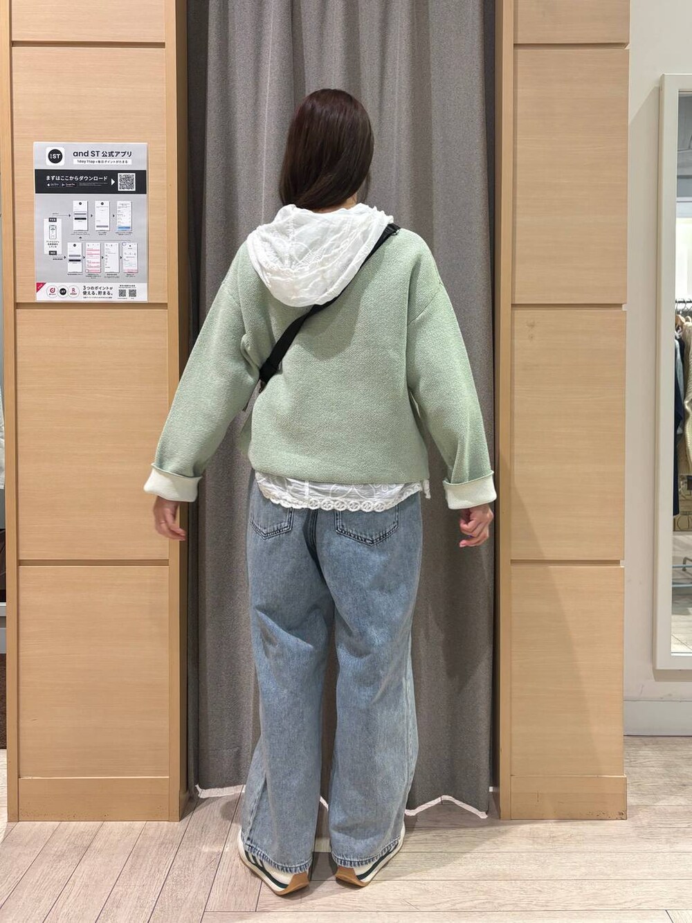 ホワイト系のスニーカー、ブルー系のデニムパンツ、ブラウン系のショルダーバッグを着用したレディースの冬コーディネートの3枚目の写真