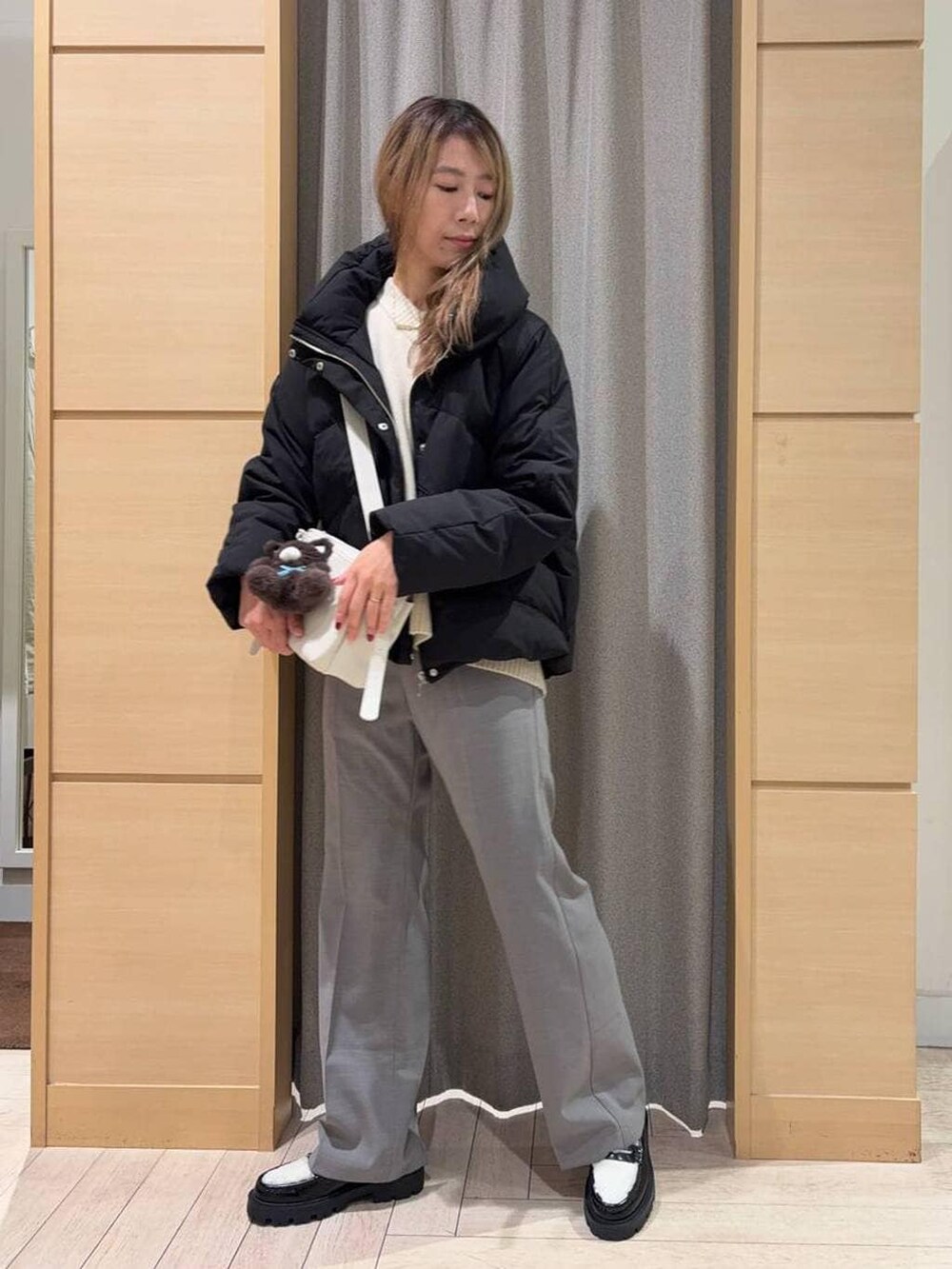 ブラック系のダウンジャケット/コート、ベージュ系のニット/セーター、ベージュ系のショルダーバッグを着用したレディースの秋コーディネートの5枚目の写真