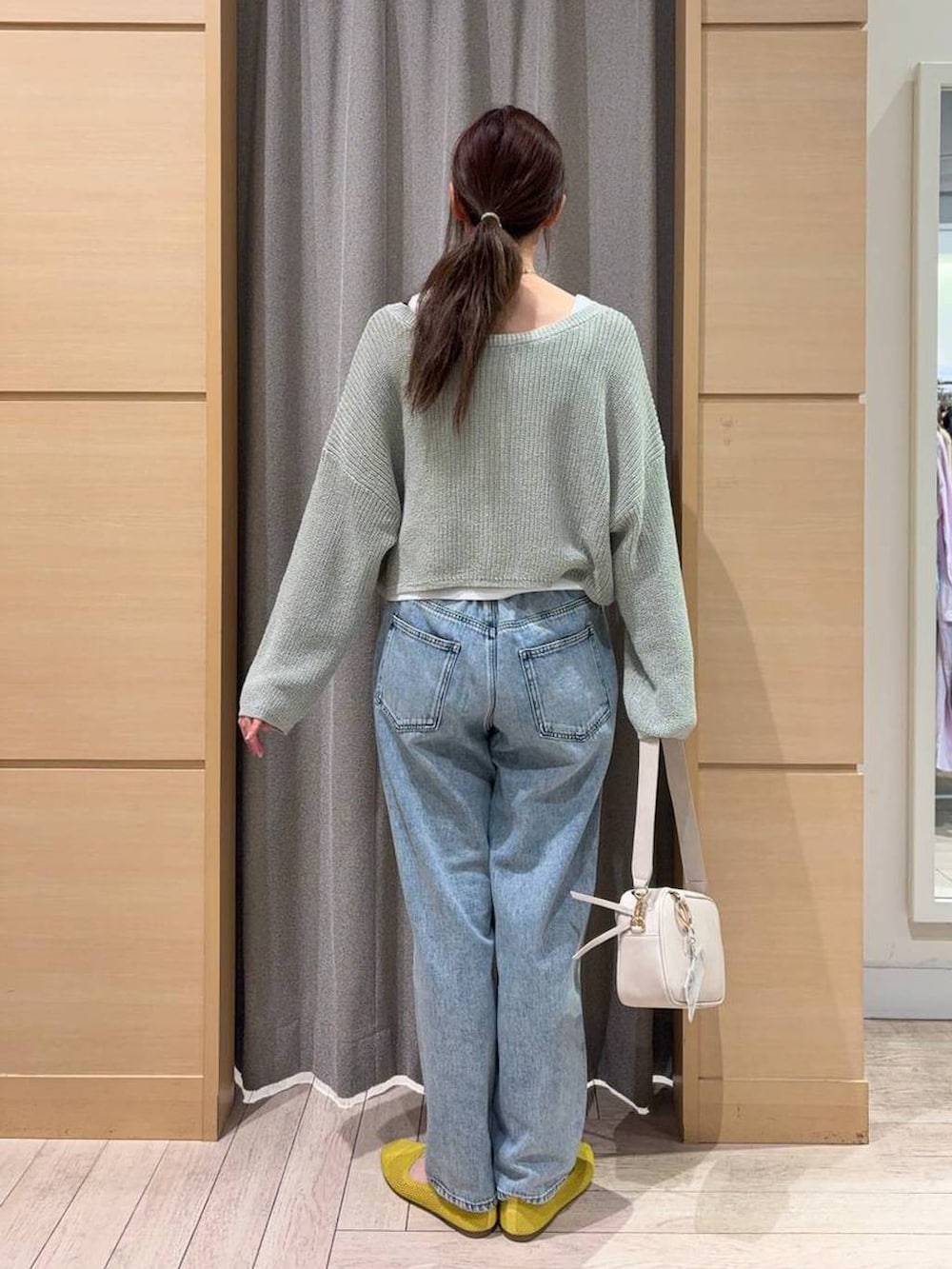ブルー系のデニムパンツ、ベージュ系のショルダーバッグ、イエロー系のパンプスを着用したレディースの春コーディネートの2枚目の写真