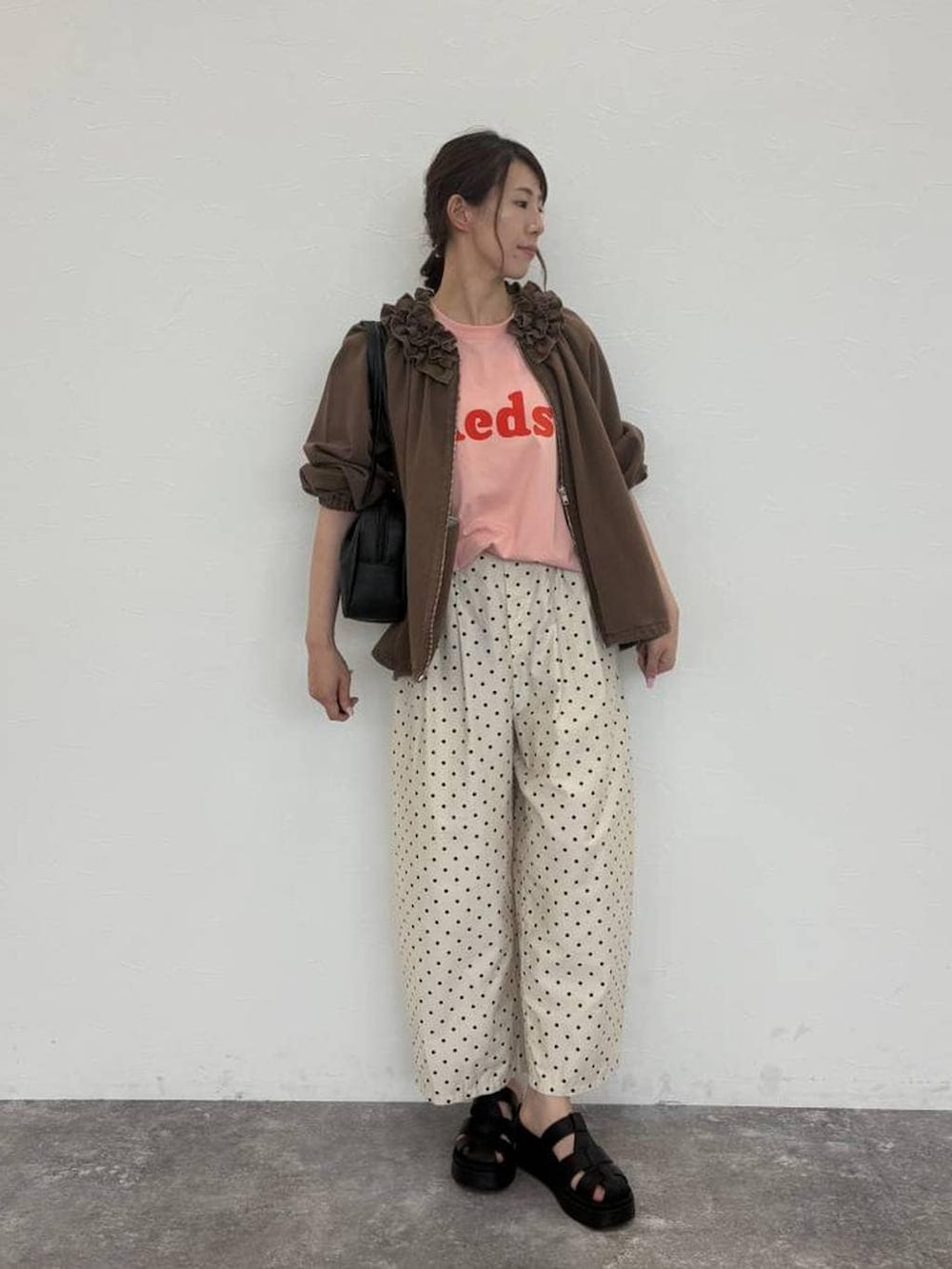 ブラック系のショルダーバッグ、ピンク系のTシャツ/カットソー、ブラウン系のブルゾンを着用したレディースの秋コーディネートの3枚目の写真