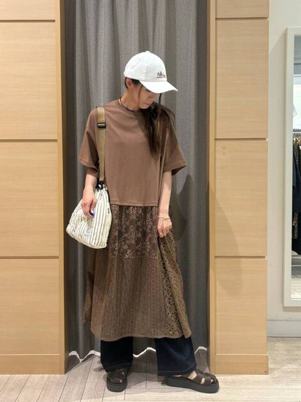 ベージュ系のショルダーバッグ、ブラウン系のサンダル、ブルー系のデニムパンツを着用したレディースの夏コーディネートの3枚目の写真