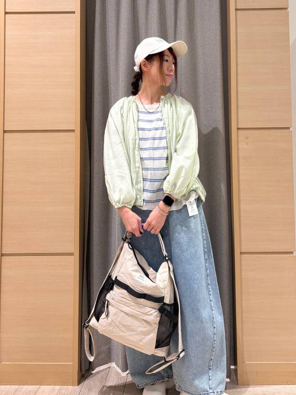 ブルー系のデニムパンツ、ベージュ系のショルダーバッグ、その他のニット/セーターを着用したレディースの春コーディネートの3枚目の写真