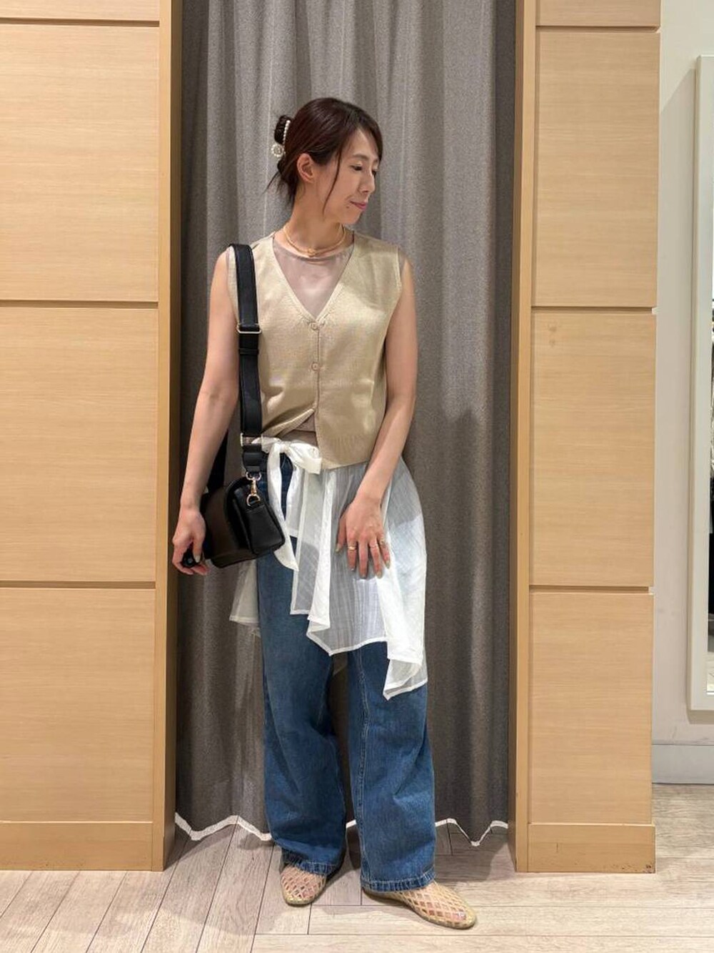 ブルー系のデニムパンツ、ブラック系のショルダーバッグ、ベージュ系のパンプスを着用したレディースの秋コーディネートの3枚目の写真
