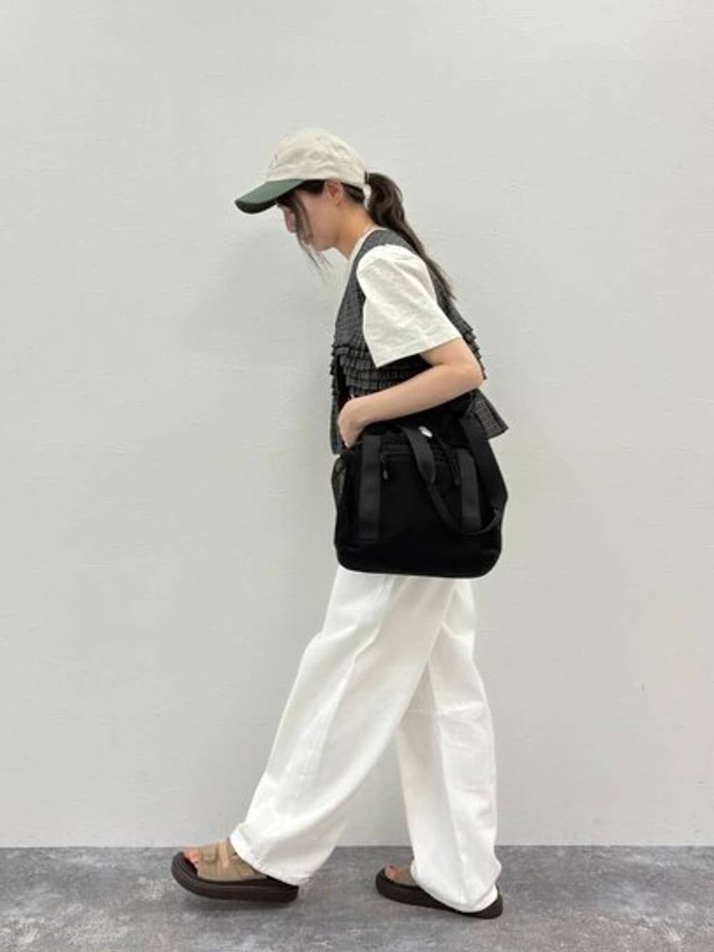 ベージュ系のサンダル、ブラック系のショルダーバッグ、ホワイト系のデニムパンツを着用したレディースの夏コーディネートの3枚目の写真