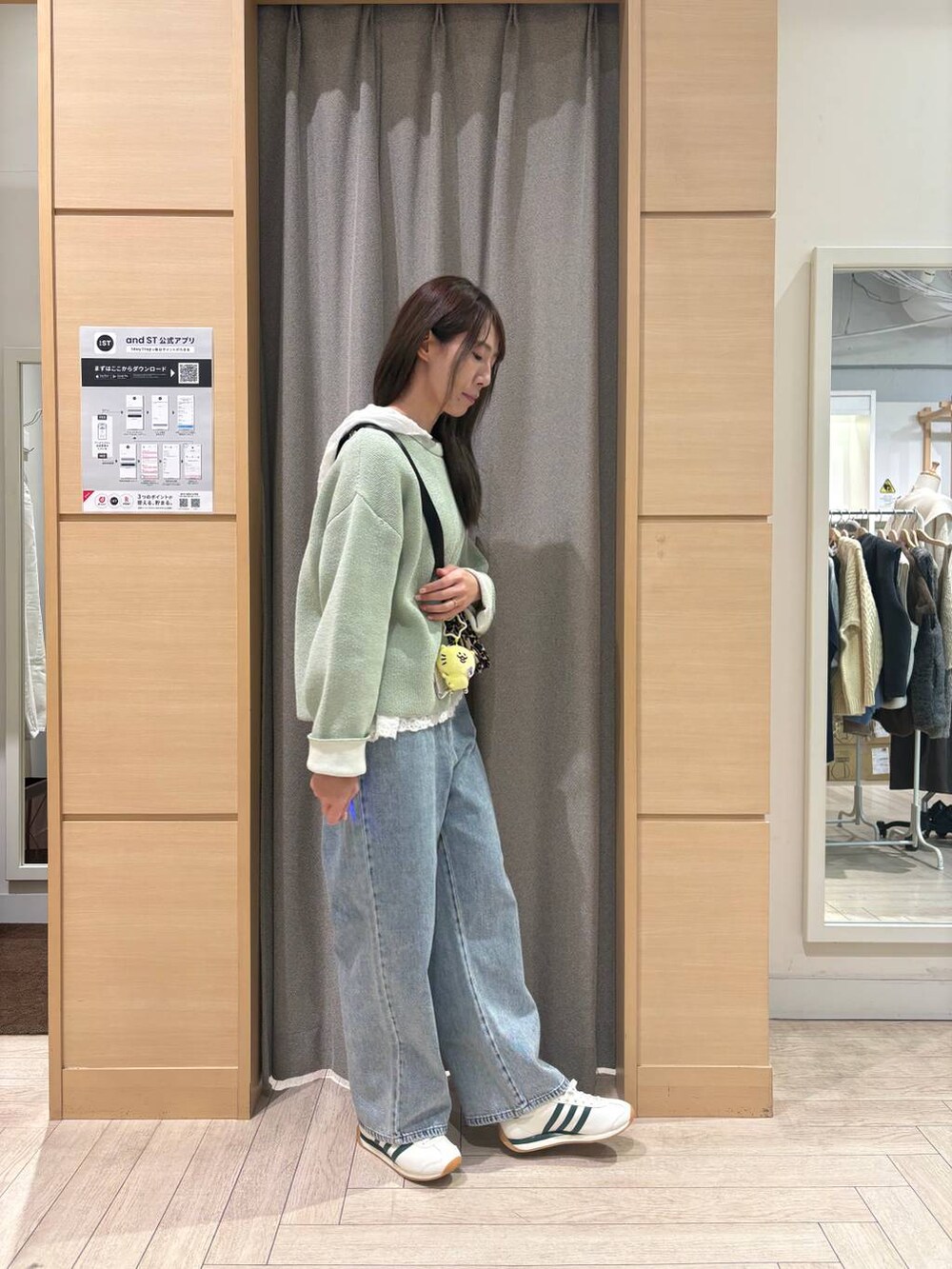 ホワイト系のスニーカー、ブルー系のデニムパンツ、ブラウン系のショルダーバッグを着用したレディースの冬コーディネートの3枚目の写真