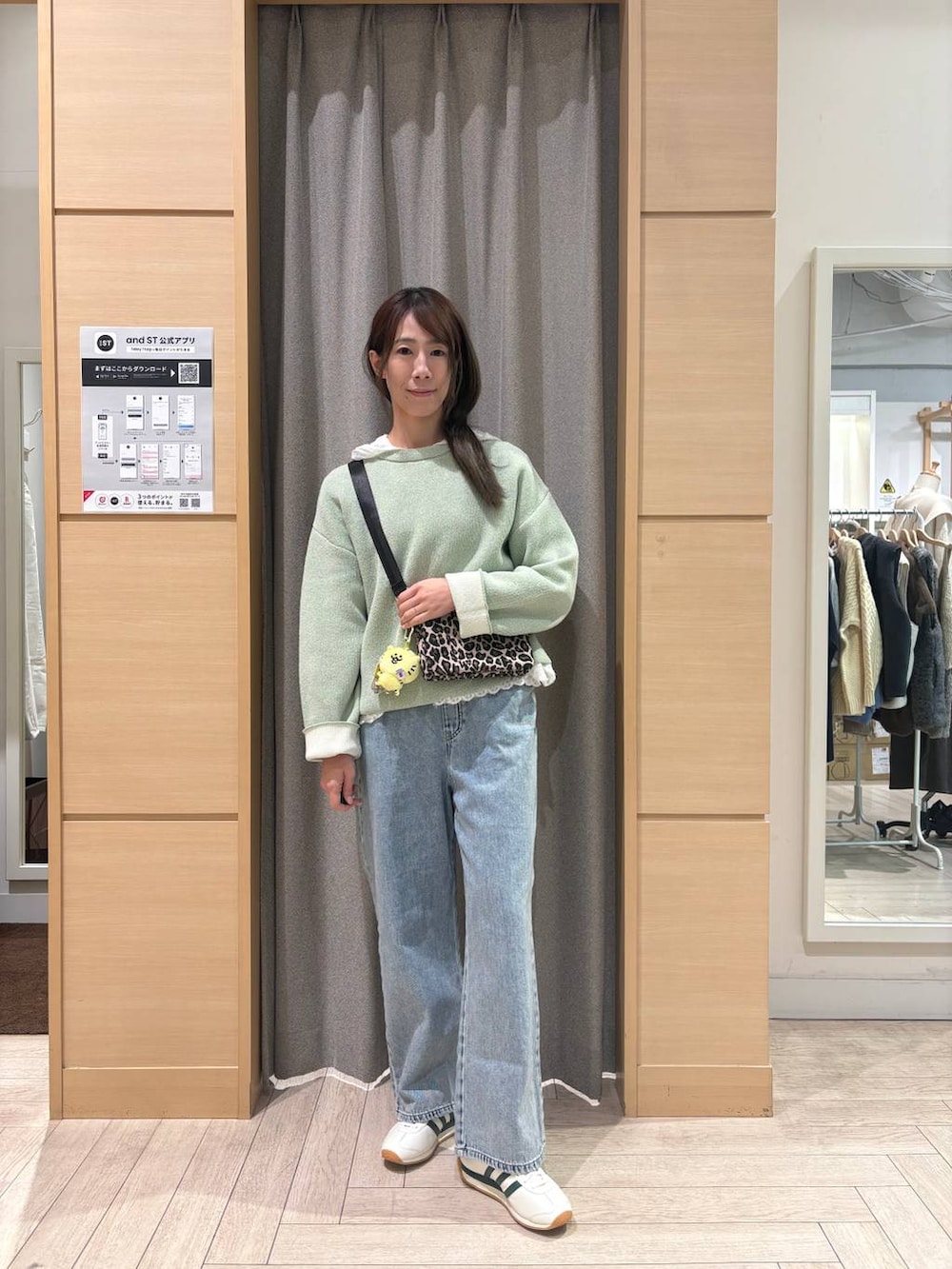 ホワイト系のスニーカー、ブルー系のデニムパンツ、ブラウン系のショルダーバッグを着用したレディースの冬コーディネートの4枚目の写真