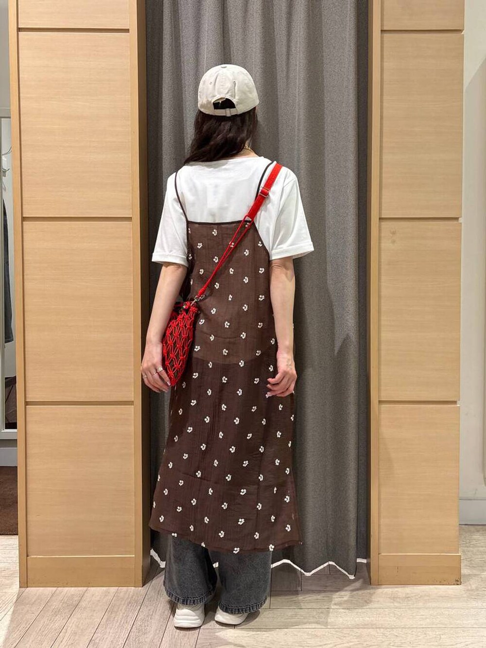 グレー系のデニムパンツ、レッド系のショルダーバッグ、ベージュ系のスニーカーを着用したレディースの春コーディネートの2枚目の写真