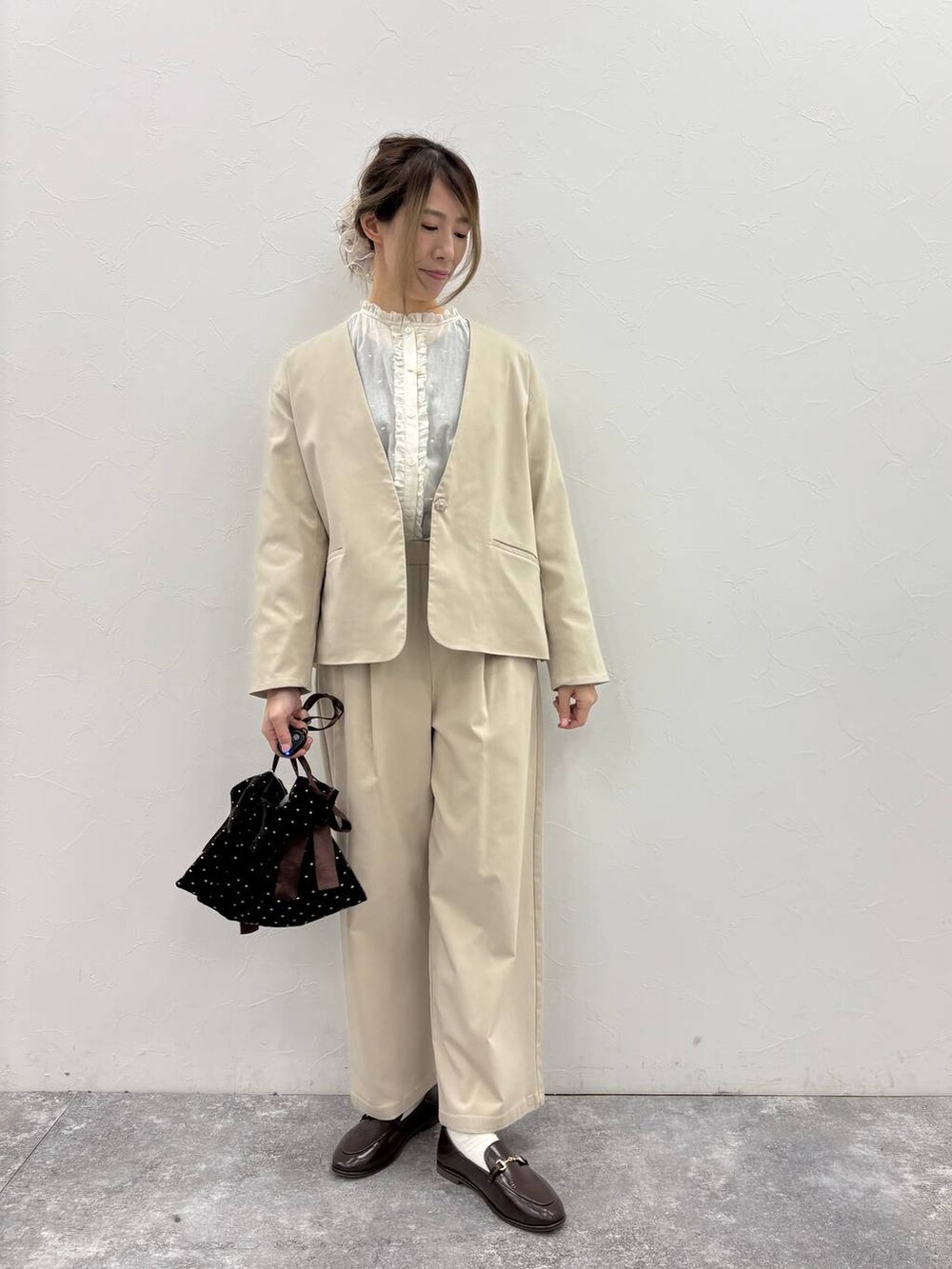 ベージュ系のスラックス、ベージュ系のノーカラージャケット、ホワイト系のシャツ/ブラウスを着用したレディースの冬コーディネートの5枚目の写真