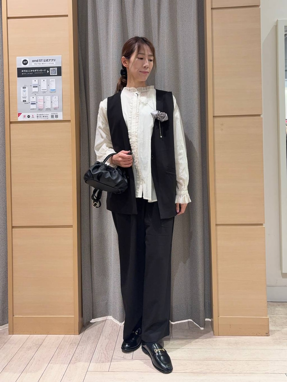 ブラック系のベスト、ブラック系のスラックス、ブラック系のショルダーバッグを着用したレディースの春コーディネートの4枚目の写真