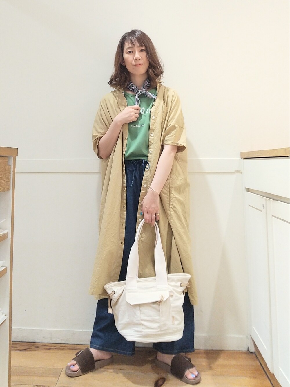 ブラウン系のサンダル、ベージュ系のトートバッグ、グリーン系のTシャツ/カットソーを着用したレディースの夏コーディネートの2枚目の写真