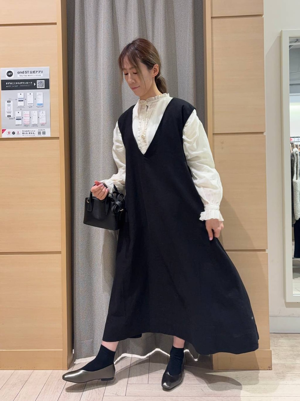 ブラック系のトートバッグ、ホワイト系のシャツ/ブラウス、ブラック系のジャンパースカートを着用したレディースの冬コーディネートの2枚目の写真