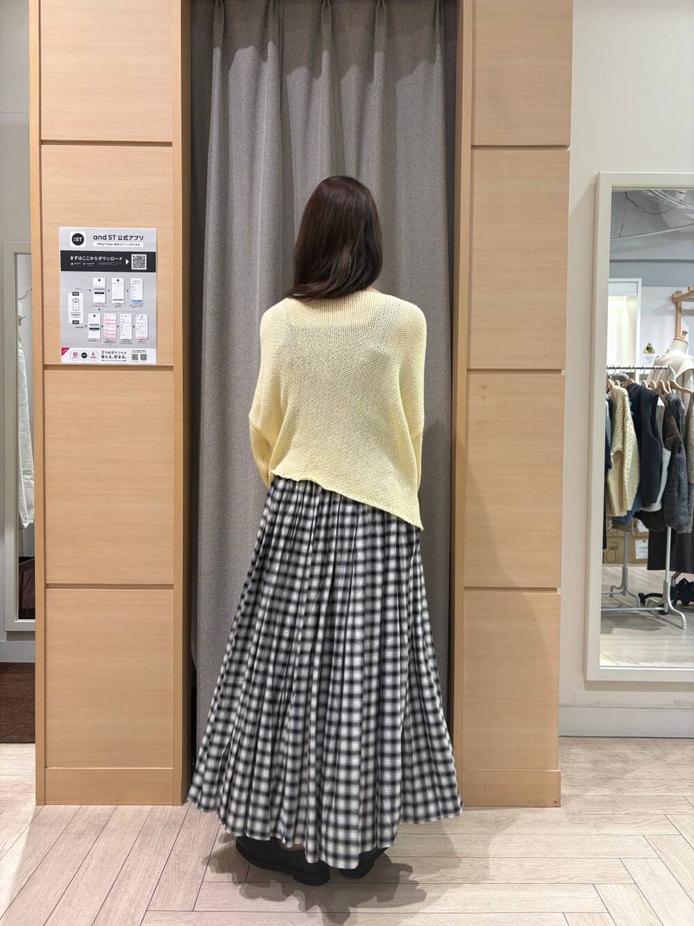 ベージュ系のショルダーバッグ、イエロー系のニット/セーター、ブラック系のスカートを着用したレディースの冬コーディネートの2枚目の写真