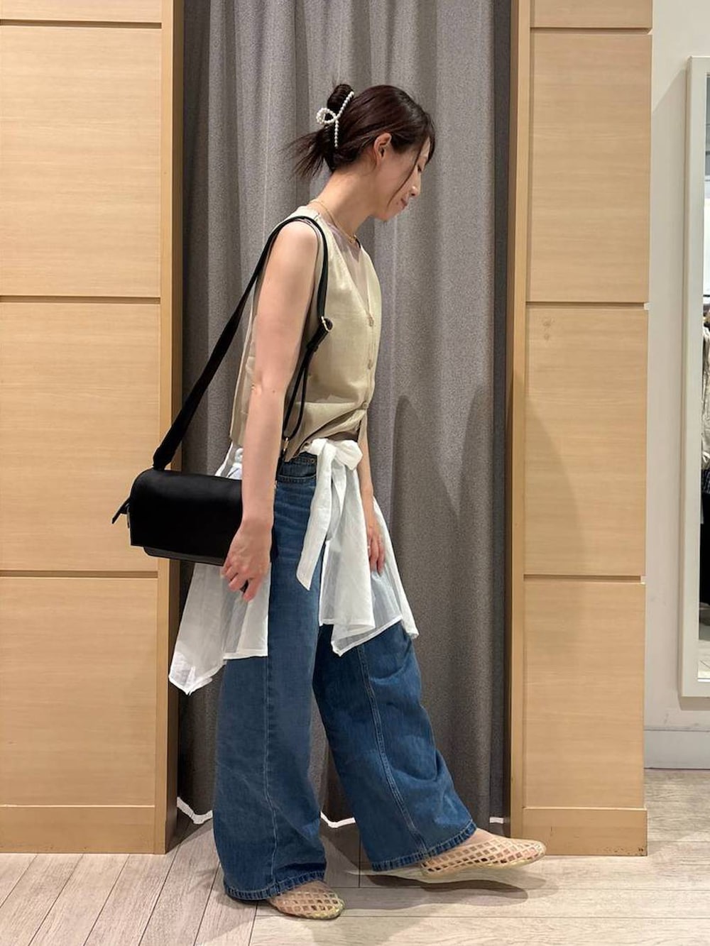 ブルー系のデニムパンツ、ブラック系のショルダーバッグ、ベージュ系のパンプスを着用したレディースの秋コーディネートの2枚目の写真