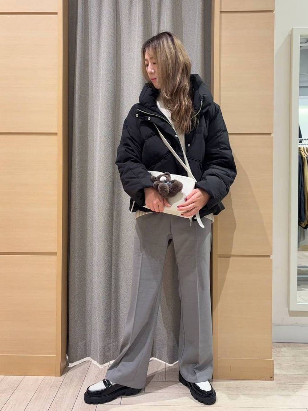 ブラック系のダウンジャケット/コート、ベージュ系のニット/セーター、ベージュ系のショルダーバッグを着用したレディースの秋コーディネートの2枚目の写真