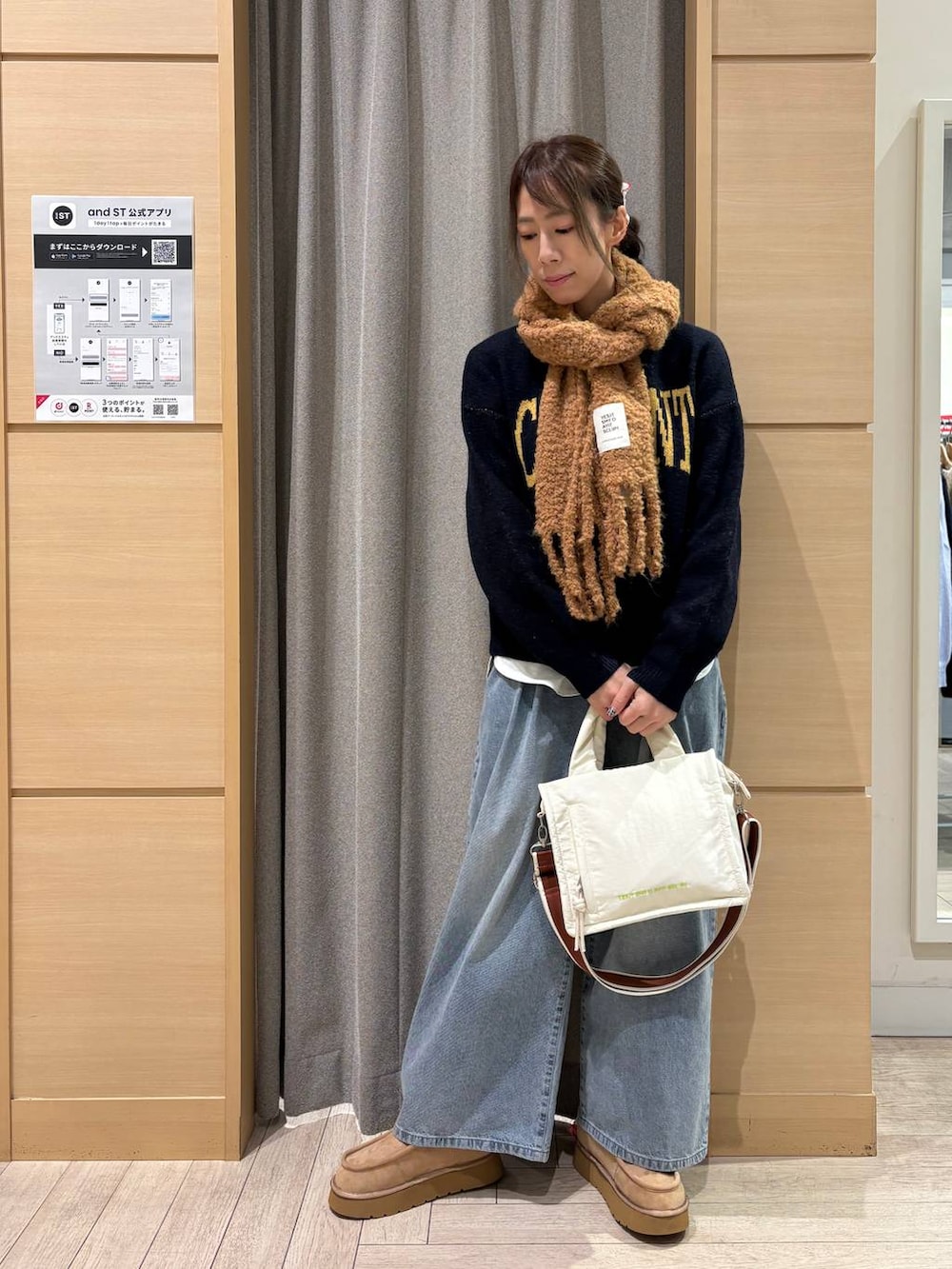 ブルー系のデニムパンツ、ベージュ系のブーツ、ベージュ系のショルダーバッグを着用したレディースの冬コーディネートの3枚目の写真