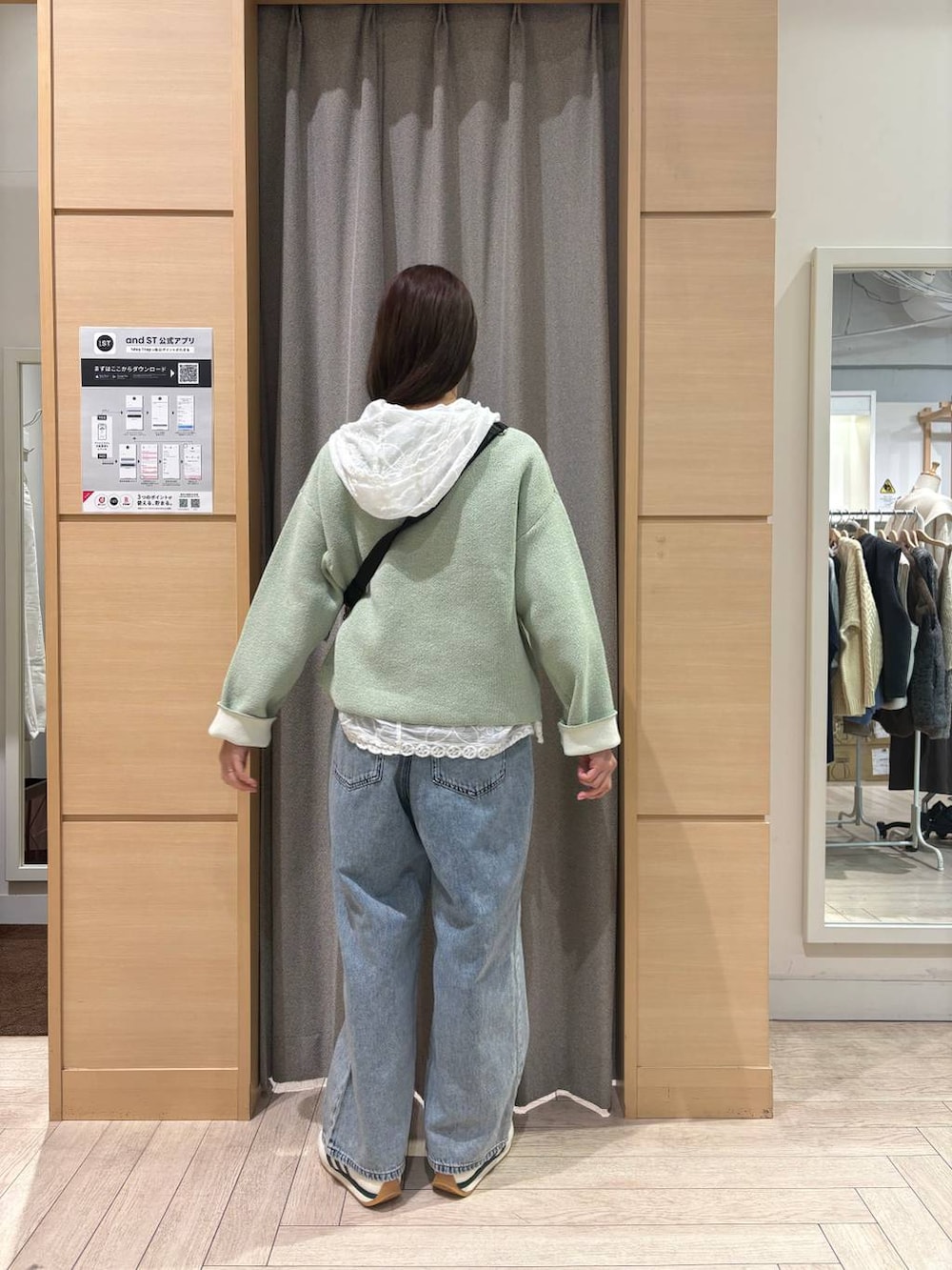 ホワイト系のスニーカー、ブルー系のデニムパンツ、ブラウン系のショルダーバッグを着用したレディースの冬コーディネートの2枚目の写真