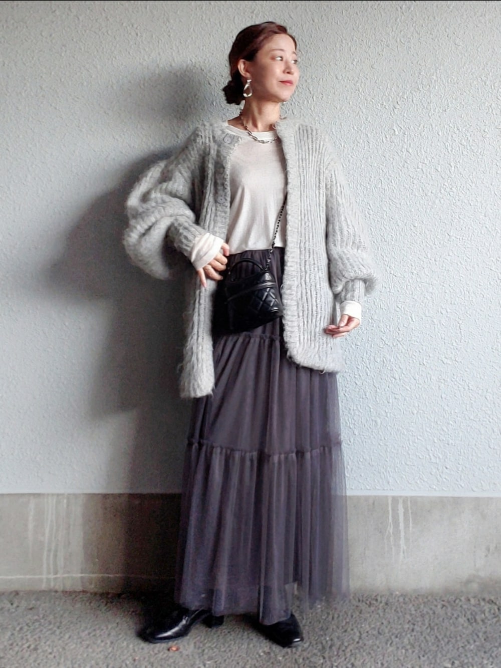 グレー系のスカート、ブラック系のブーツ、ホワイト系のTシャツ/カットソーを着用したレディースの秋コーディネートの2枚目の写真