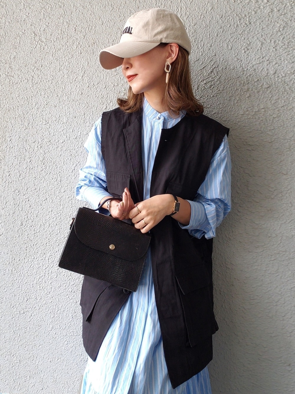 ブラック系のベスト、ブルー系のシャツワンピース、ブラック系のローファーを着用したレディースの春コーディネートの3枚目の写真
