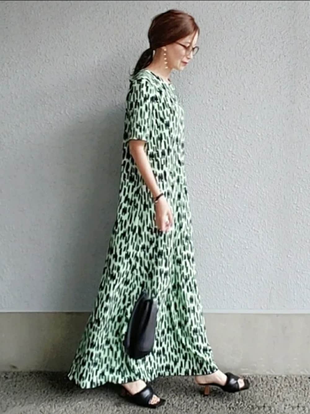 グリーン系のワンピース、ブラック系のバッグ、ブラック系のサンダルを着用したレディースの春コーディネートの2枚目の写真