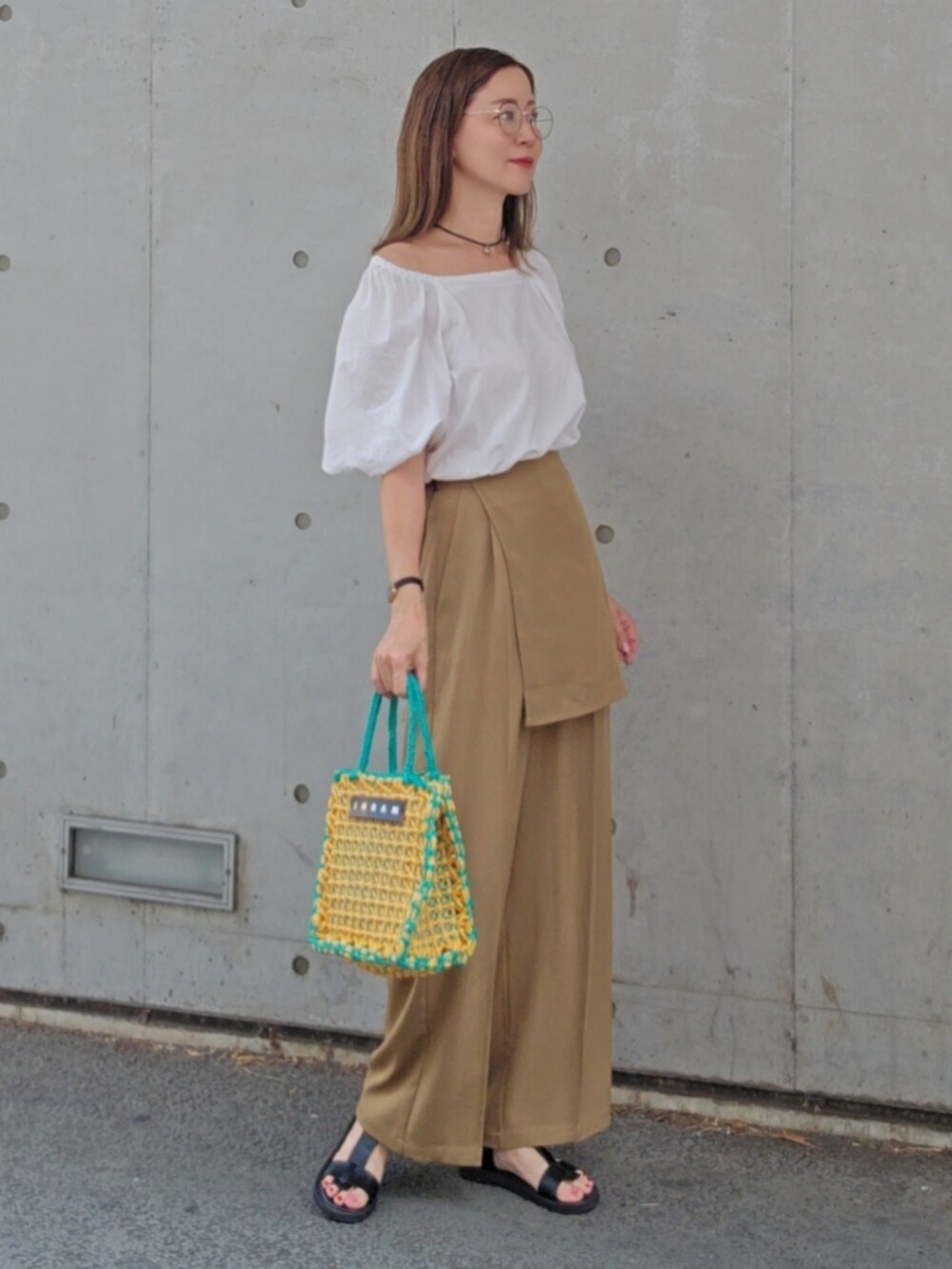 ベージュ系のその他パンツ、イエロー系のバッグ、ブラック系のサンダルを着用したレディースの夏コーディネートの3枚目の写真